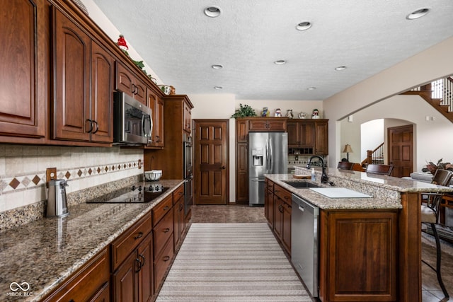 5194 Orahood Ct, Plainfield, IN 46168 - kitchen featuring stainless steel appliances, a breakfast bar, arched walkways, backsplash, and light stone countertops