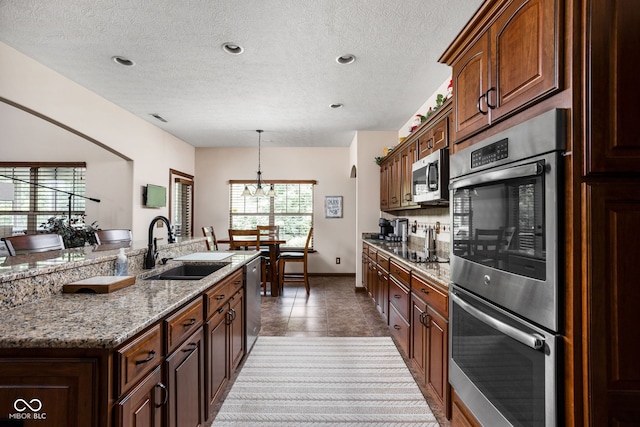 5194 Orahood Ct, Plainfield, IN 46168 - kitchen with appliances with stainless steel finishes, a textured ceiling, a chandelier, decorative light fixtures, and a kitchen island with sink