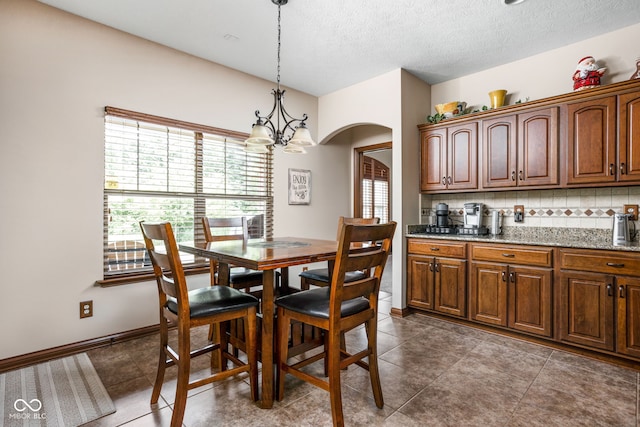 5194 Orahood Ct, Plainfield, IN 46168 - dining area with arched walkways, a chandelier, a textured ceiling, and dark tile patterned floors