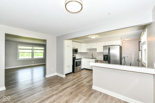 1543 W 79th St, Indianapolis, IN 46260 - kitchen with appliances with stainless steel finishes, light wood-type flooring, a peninsula, white cabinets, and light countertops