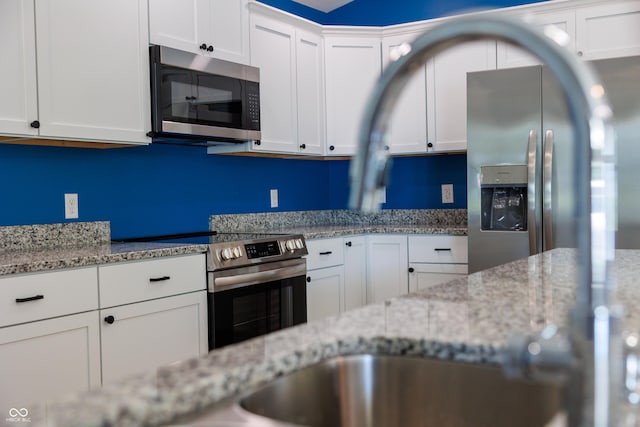 5122 W Legrande Ave, Indianapolis, IN 46241 - kitchen with stainless steel appliances, white cabinetry, and light stone countertops