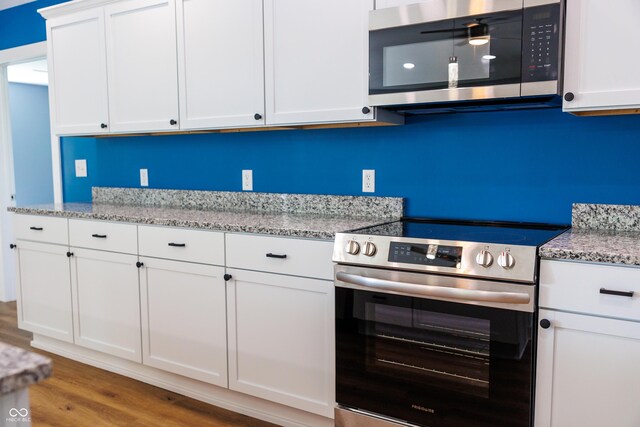 5122 W Legrande Ave, Indianapolis, IN 46241 - kitchen featuring appliances with stainless steel finishes, wood finished floors, white cabinetry, and light stone counters