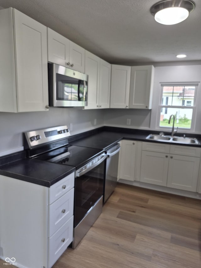 1501 California St, Columbus, IN 47201 - kitchen featuring stainless steel appliances, white cabinets, dark countertops, light wood-style floors, and recessed lighting