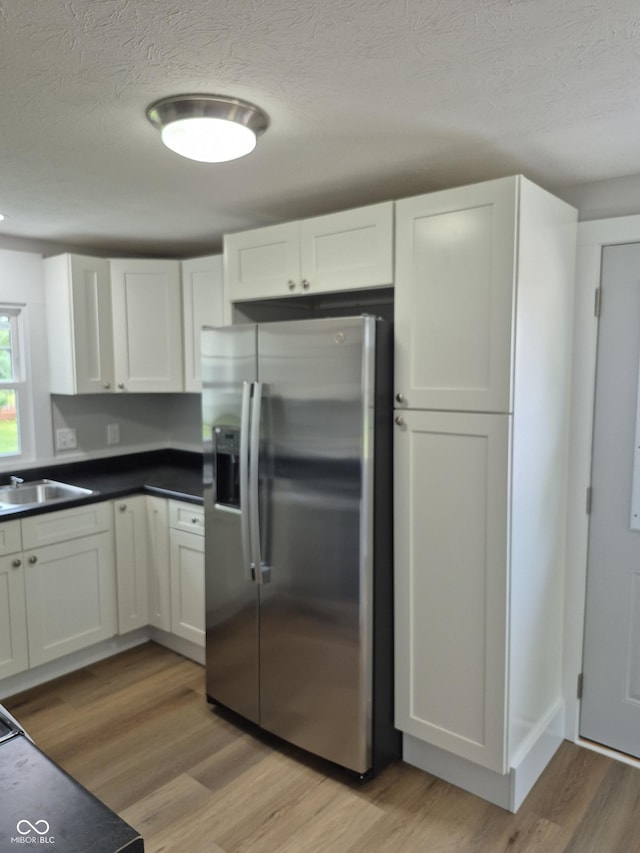 1501 California St, Columbus, IN 47201 - kitchen featuring stainless steel refrigerator with ice dispenser, a textured ceiling, light wood-style flooring, white cabinets, and dark countertops