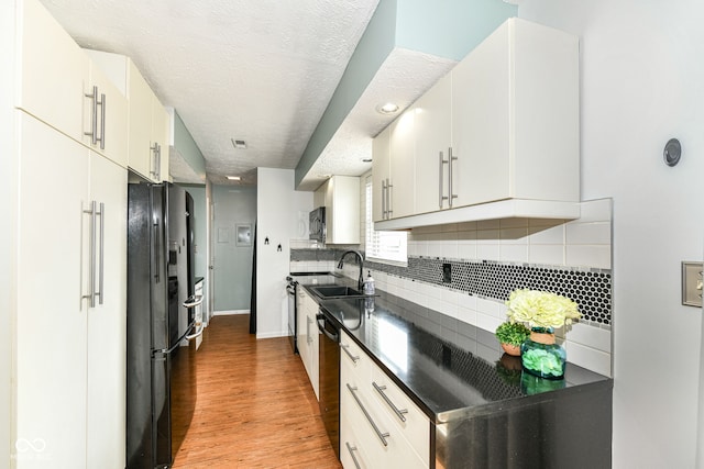 1124 Paradise Ct Unit B, Greenwood, IN 46143 - kitchen with black fridge, dark countertops, dishwasher, light wood finished floors, and backsplash