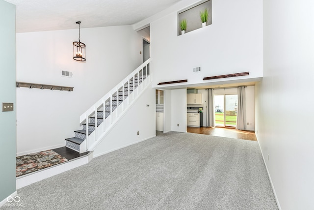 1124 Paradise Ct Unit B, Greenwood, IN 46143 - unfurnished living room with high vaulted ceiling, carpet flooring, stairway, and a chandelier