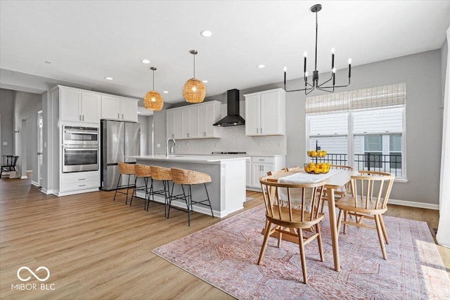 4253 Ironclad Dr, Bargersville, IN 46106 - kitchen featuring wall chimney range hood, appliances with stainless steel finishes, light countertops, a center island with sink, and tasteful backsplash