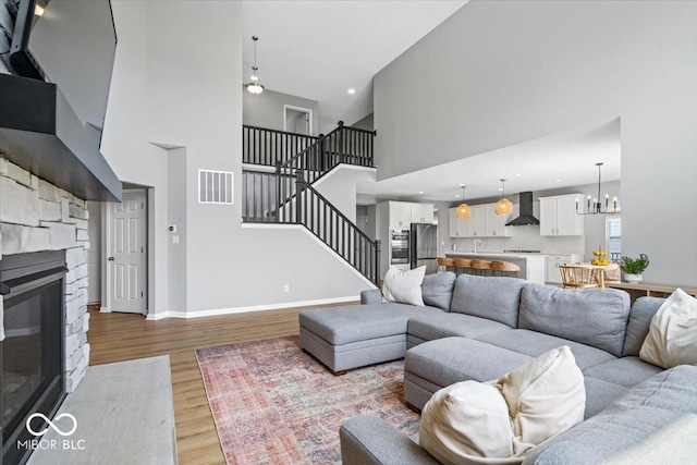 4253 Ironclad Dr, Bargersville, IN 46106 - living area featuring a high ceiling, stairs, light wood-style flooring, a fireplace, and a chandelier