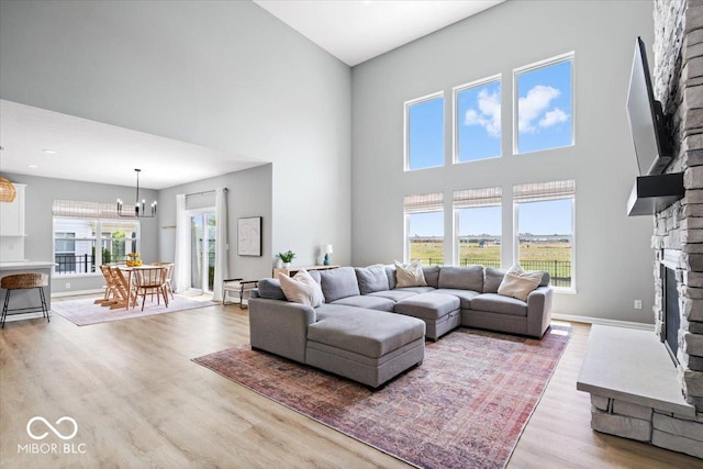 4253 Ironclad Dr, Bargersville, IN 46106 - living room featuring a fireplace, a towering ceiling, light wood-type flooring, and a chandelier