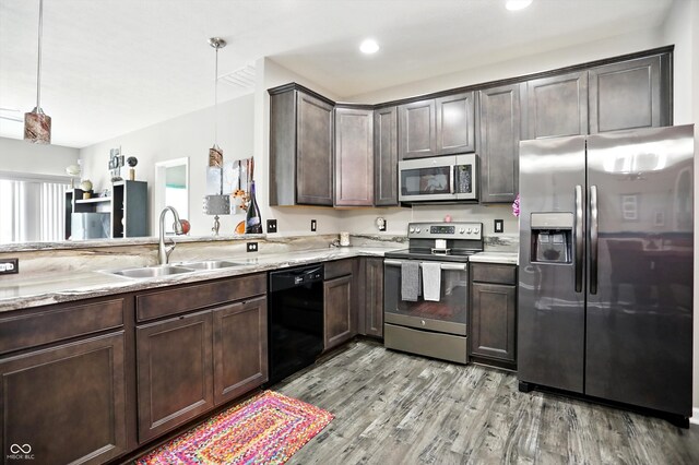 6315 Emerald Field Way, Indianapolis, IN 46221 - kitchen with stainless steel appliances, dark brown cabinets, light stone counters, light wood finished floors, and hanging light fixtures