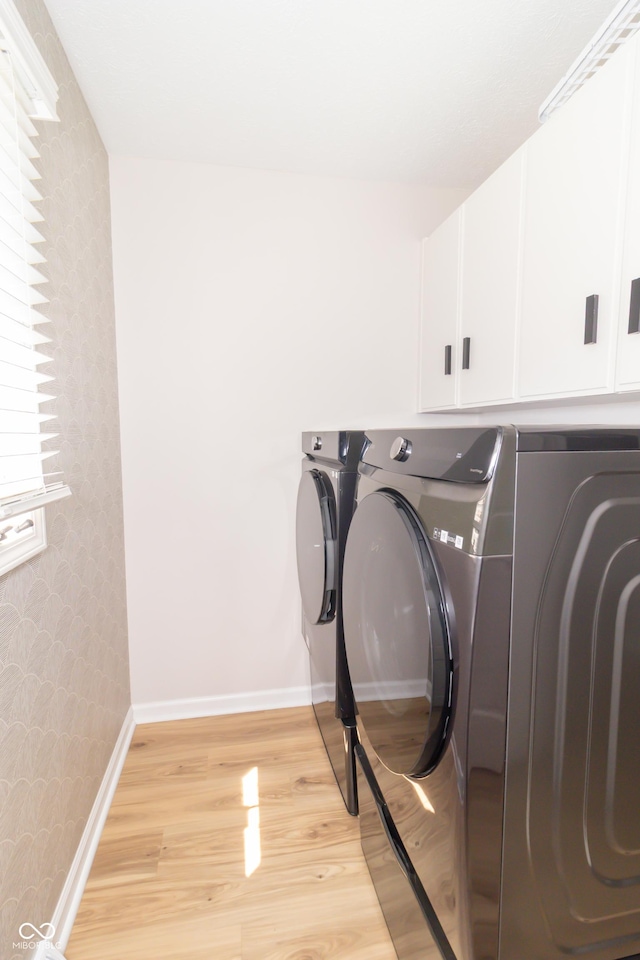 8429 Catamaran Dr, Indianapolis, IN 46236 - washroom with wallpapered walls, washing machine and dryer, cabinet space, and light wood-type flooring