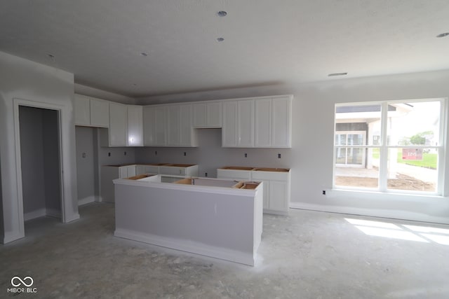 12524 Morning Ridge Way, Noblesville, IN 46060 - kitchen featuring unfinished concrete floors, a kitchen island, and white cabinets