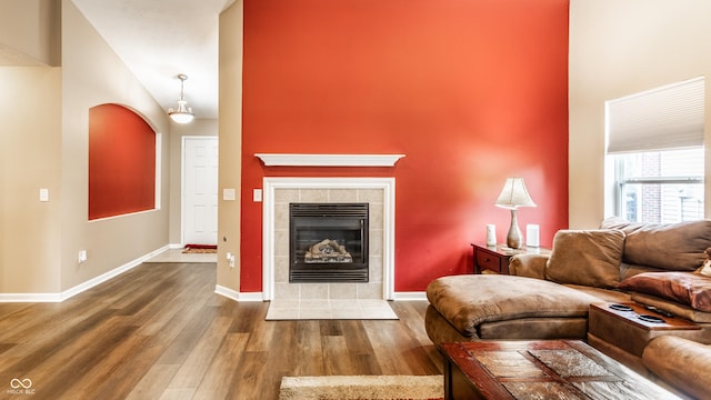 8116 Harshaw Dr, Indianapolis, IN 46239 - living area with wood finished floors, a towering ceiling, a tiled fireplace, and arched walkways