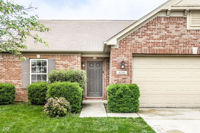 8116 Harshaw Dr, Indianapolis, IN 46239 - entrance to property featuring brick siding, a garage, driveway, and a shingled roof