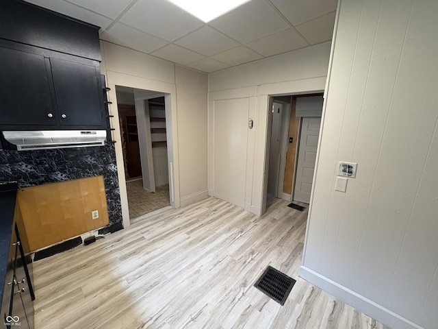 807 N Elm St, Muncie, IN 47305 - kitchen with dark cabinets, light wood-type flooring, a drop ceiling, a decorative wall, and under cabinet range hood