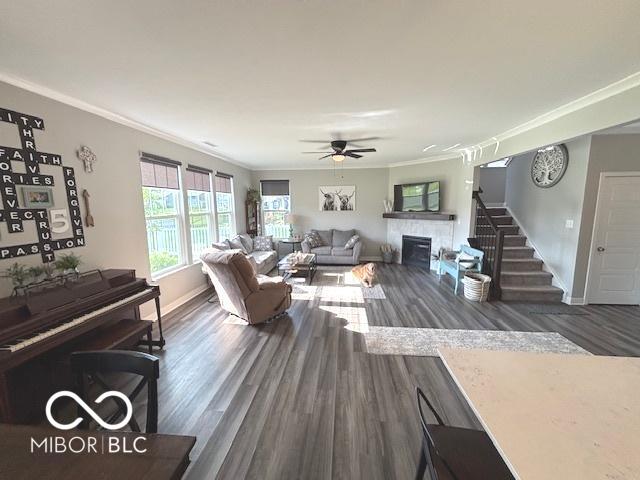520 Ferndale Ln, Danville, IN 46122 - living room featuring ceiling fan, wood finished floors, crown molding, a glass covered fireplace, and stairs