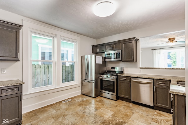 525 Orange St, Indianapolis, IN 46203 - kitchen featuring stainless steel appliances, plenty of natural light, dark brown cabinets, and stone finish flooring