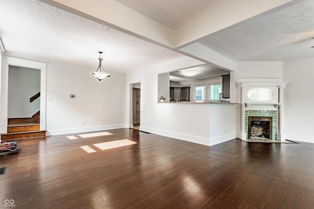 525 Orange St, Indianapolis, IN 46203 - unfurnished living room featuring stairway, dark wood-style flooring, a tile fireplace, and a textured ceiling