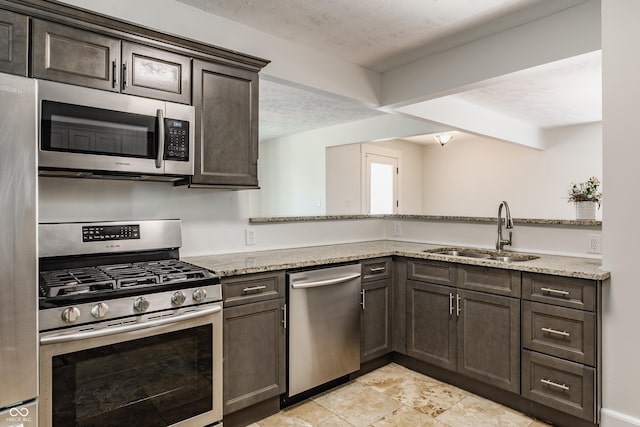 525 Orange St, Indianapolis, IN 46203 - kitchen with appliances with stainless steel finishes, dark brown cabinetry, light stone countertops, and a peninsula
