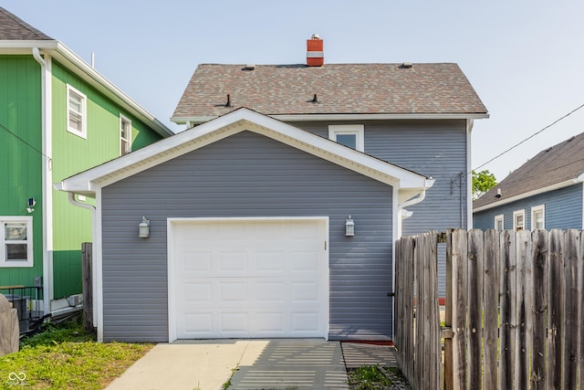 525 Orange St, Indianapolis, IN 46203 - back of house featuring a chimney, an outdoor structure, a detached garage, concrete driveway, and a shingled roof