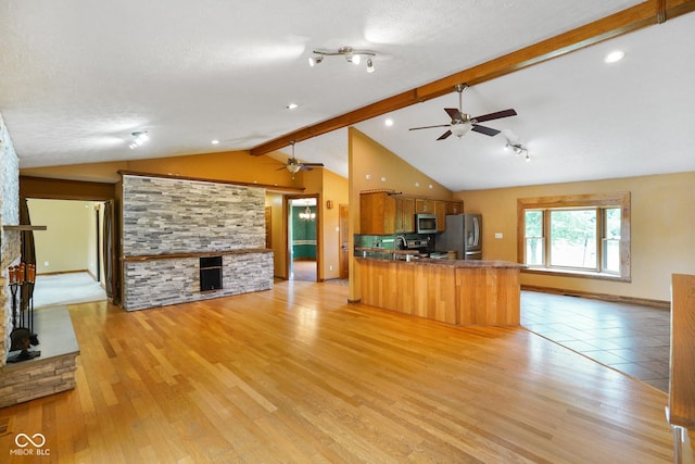 12196 N Beth Ann Dr, Camby, IN 46113 - kitchen with appliances with stainless steel finishes, a fireplace, open floor plan, ceiling fan, and a textured ceiling