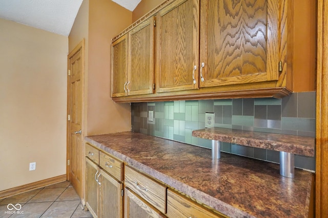 12196 N Beth Ann Dr, Camby, IN 46113 - kitchen featuring backsplash, dark countertops, brown cabinets, and light tile patterned floors