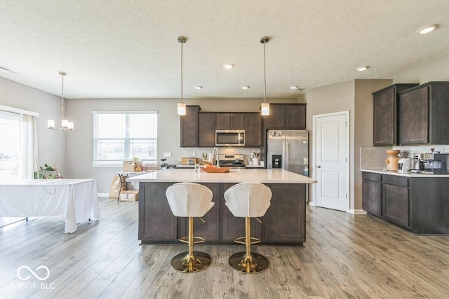 1758 Pelham Dr, Greenwood, IN 46143 - kitchen featuring stainless steel appliances, dark brown cabinets, light wood finished floors, light countertops, and a textured ceiling