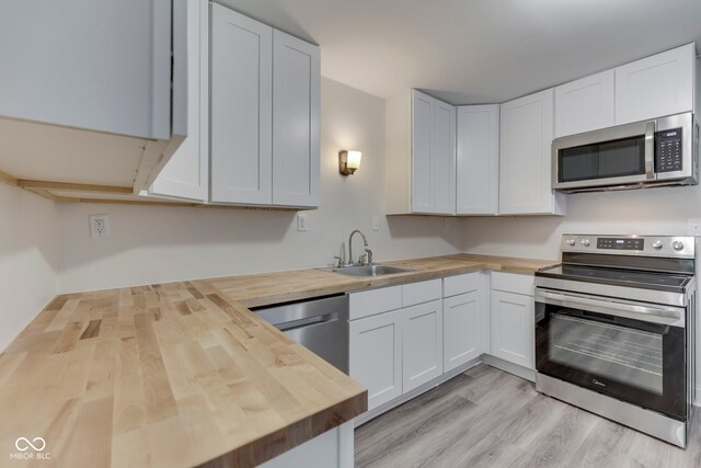 2245 N Ritter Ave, Indianapolis, IN 46218 - kitchen with butcher block counters, stainless steel appliances, light wood-style flooring, and white cabinets