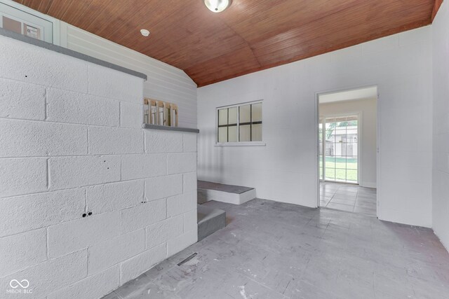 2245 N Ritter Ave, Indianapolis, IN 46218 - unfurnished living room with wooden ceiling, unfinished concrete flooring, vaulted ceiling, stairs, and concrete block wall
