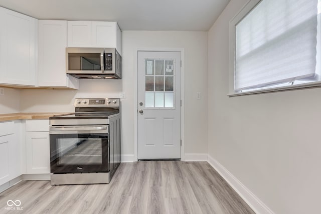 2245 N Ritter Ave, Indianapolis, IN 46218 - kitchen featuring appliances with stainless steel finishes, light wood finished floors, white cabinets, and butcher block countertops
