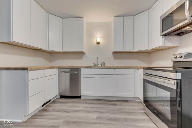 2245 N Ritter Ave, Indianapolis, IN 46218 - kitchen with stainless steel appliances, white cabinetry, and light wood-type flooring