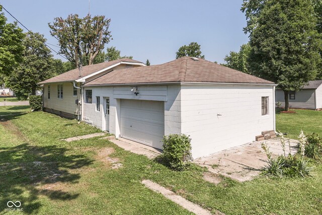 2245 N Ritter Ave, Indianapolis, IN 46218 - view of side of home with a lawn, a shingled roof, a detached garage, and concrete block siding