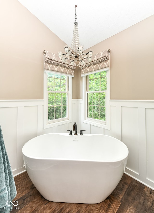 9825 Covington Blvd, Fishers, IN 46037 - full bathroom with wainscoting, a decorative wall, a chandelier, a soaking tub, and wood finished floors