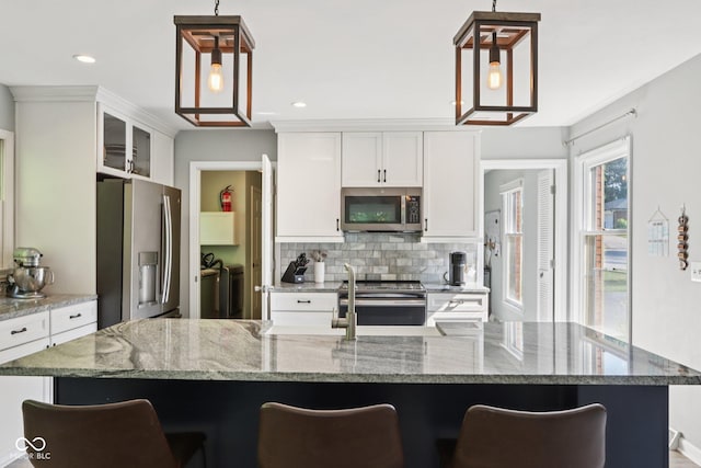 7029 Kingswood Cir, Indianapolis, IN 46256 - kitchen featuring appliances with stainless steel finishes, washer and dryer, backsplash, a kitchen breakfast bar, and white cabinetry
