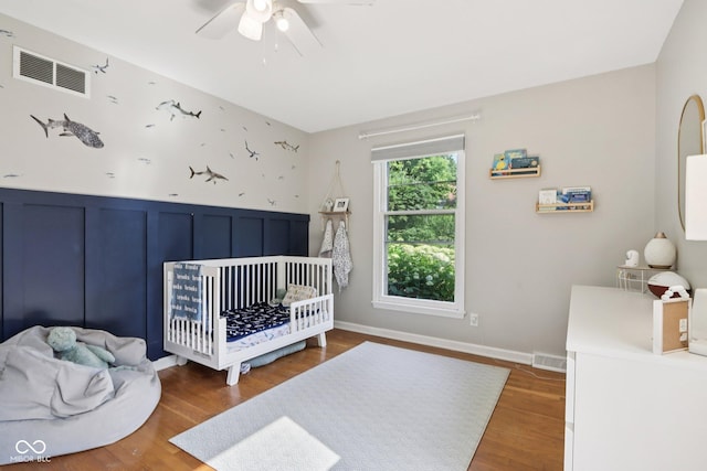 7029 Kingswood Cir, Indianapolis, IN 46256 - bedroom featuring wood finished floors, ceiling fan, and a crib