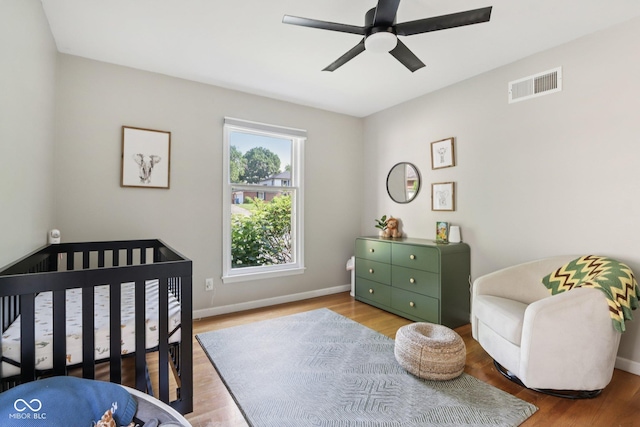 7029 Kingswood Cir, Indianapolis, IN 46256 - bedroom featuring wood finished floors, ceiling fan, and a nursery area