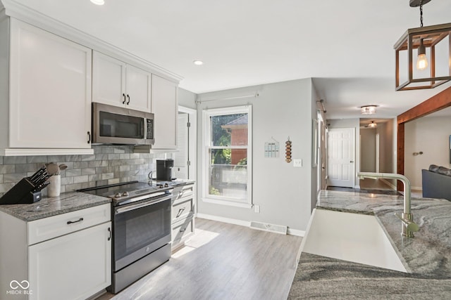 7029 Kingswood Cir, Indianapolis, IN 46256 - kitchen featuring appliances with stainless steel finishes, tasteful backsplash, white cabinetry, light stone countertops, and recessed lighting
