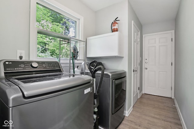 7029 Kingswood Cir, Indianapolis, IN 46256 - washroom featuring washing machine and dryer, light wood finished floors, and cabinet space