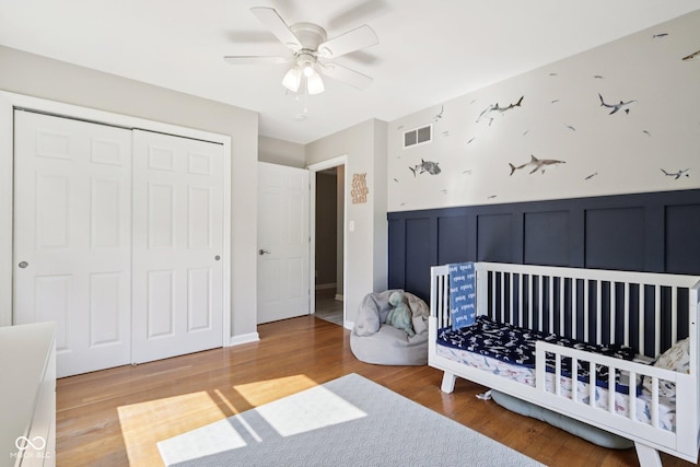 7029 Kingswood Cir, Indianapolis, IN 46256 - bedroom featuring a closet, a wainscoted wall, a decorative wall, wood finished floors, and a nursery area