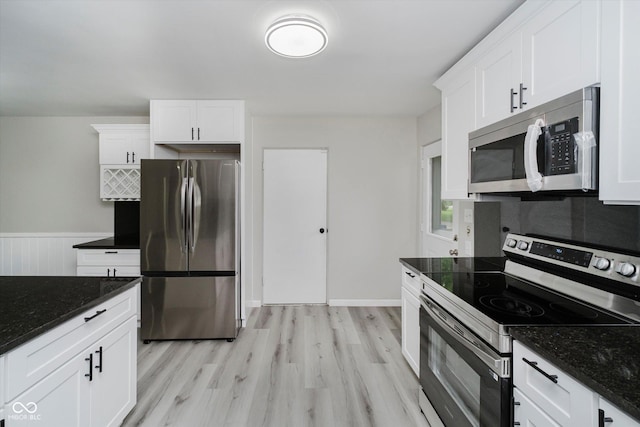 91 N Raceway Rd, Indianapolis, IN 46234 - kitchen featuring stainless steel appliances, light wood finished floors, white cabinets, dark stone counters, and wainscoting