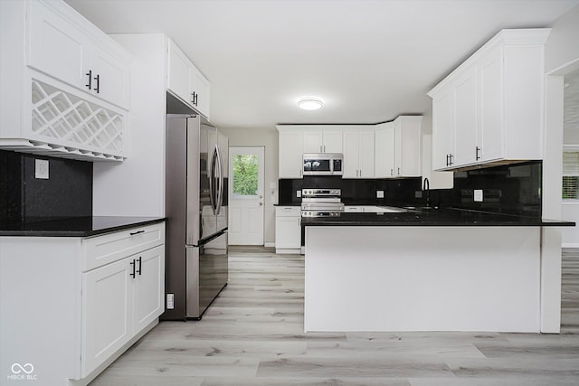 91 N Raceway Rd, Indianapolis, IN 46234 - kitchen with stainless steel appliances, light wood-style floors, decorative backsplash, a peninsula, and white cabinetry