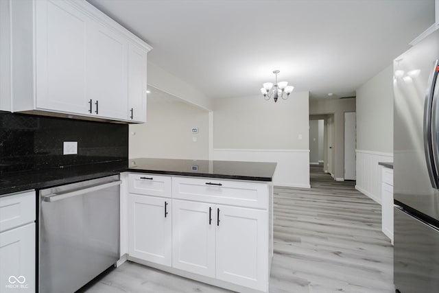 91 N Raceway Rd, Indianapolis, IN 46234 - kitchen with stainless steel appliances, a peninsula, a chandelier, white cabinetry, and light wood-style flooring