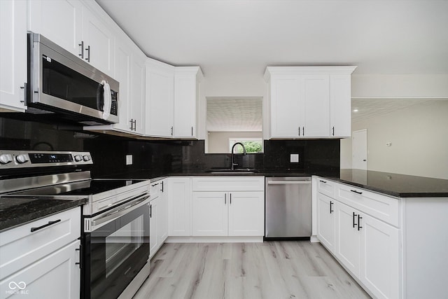 91 N Raceway Rd, Indianapolis, IN 46234 - kitchen with appliances with stainless steel finishes, a peninsula, white cabinets, tasteful backsplash, and light wood-type flooring