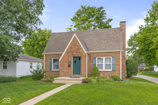 1944 Union St, Columbus, IN 47201 - tudor home featuring brick siding, roof with shingles, a chimney, and a front yard