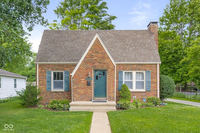 1944 Union St, Columbus, IN 47201 - tudor-style house featuring brick siding, roof with shingles, a chimney, and a front yard