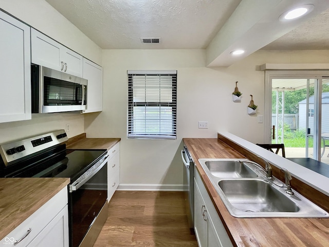 7392 S Meridian St, Indianapolis, IN 46217 - kitchen featuring appliances with stainless steel finishes, wood counters, dark wood-style flooring, a textured ceiling, and white cabinetry