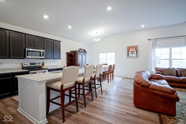 6608 W Shoreline Ct, Greenfield, IN 46140 - kitchen featuring appliances with stainless steel finishes, lofted ceiling, a breakfast bar area, a chandelier, and light wood finished floors