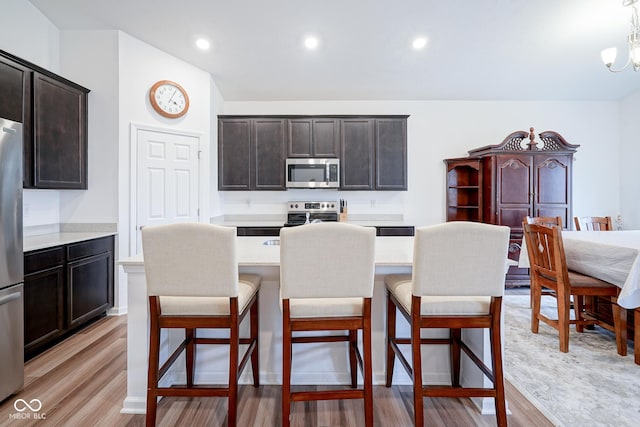 6608 W Shoreline Ct, Greenfield, IN 46140 - kitchen featuring appliances with stainless steel finishes, a breakfast bar, a center island with sink, light countertops, and recessed lighting