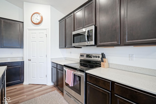6608 W Shoreline Ct, Greenfield, IN 46140 - kitchen with appliances with stainless steel finishes, light wood-type flooring, dark brown cabinetry, light stone counters, and vaulted ceiling