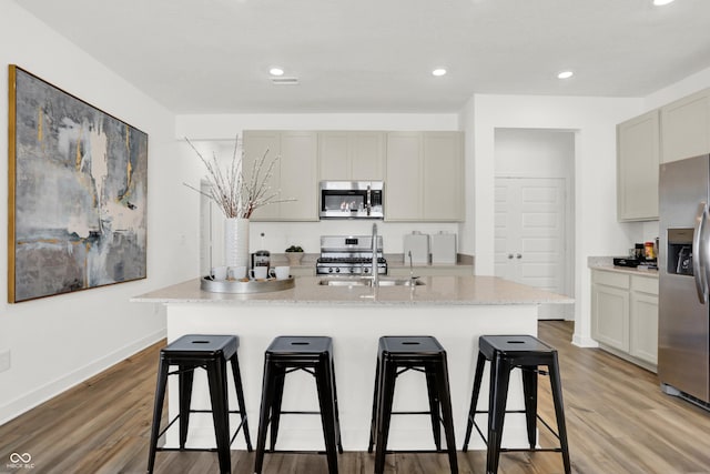 703 Penrose Pl, Danville, IN 46122 - kitchen featuring appliances with stainless steel finishes, a kitchen bar, light wood-style floors, a kitchen island with sink, and recessed lighting